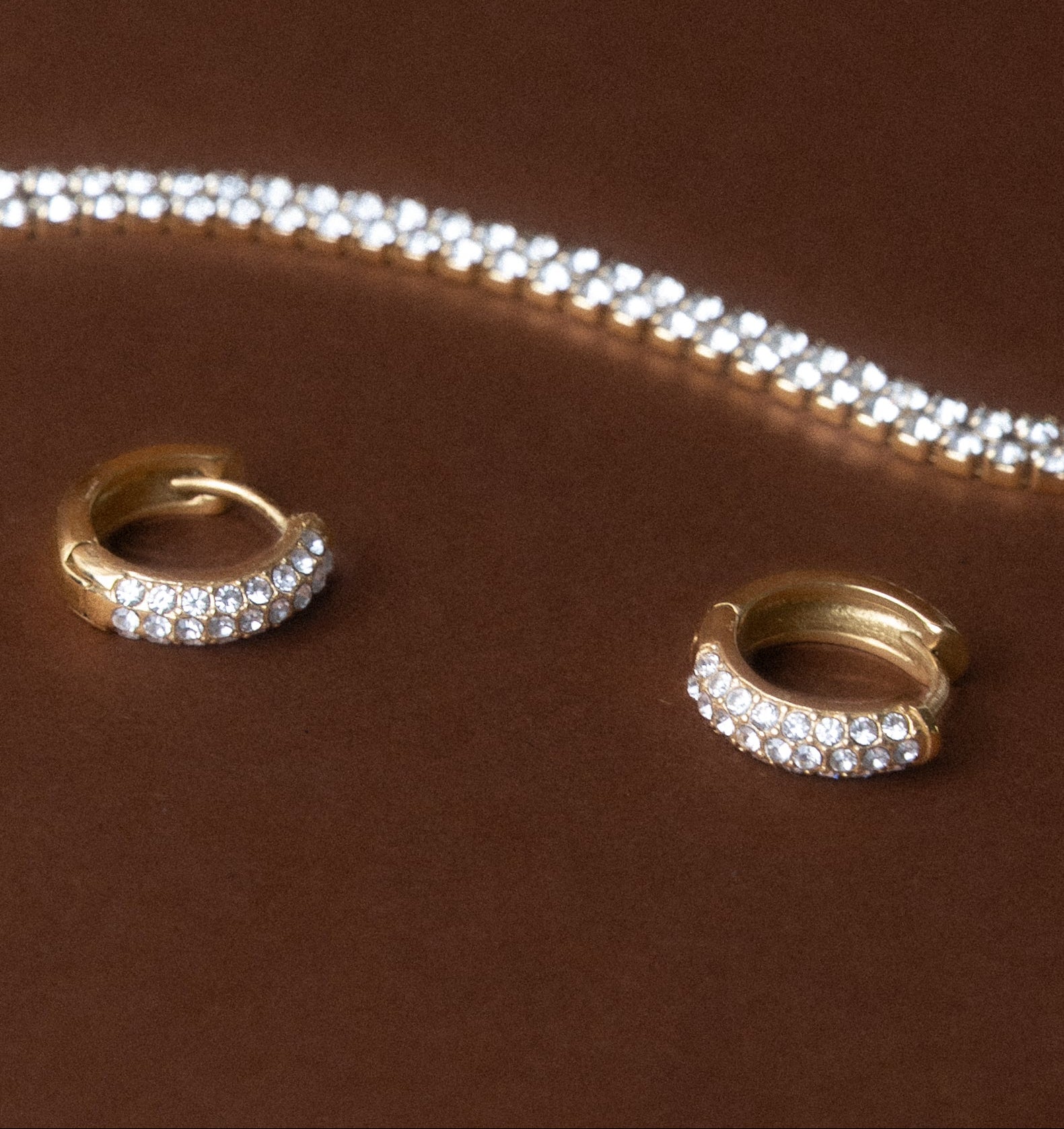 Pavé-Zirkonia Huggies in Gold, mit Tennis-Kette auf braunem Hintergrund – Edelstahl, farbbeständig | The Muse Mood